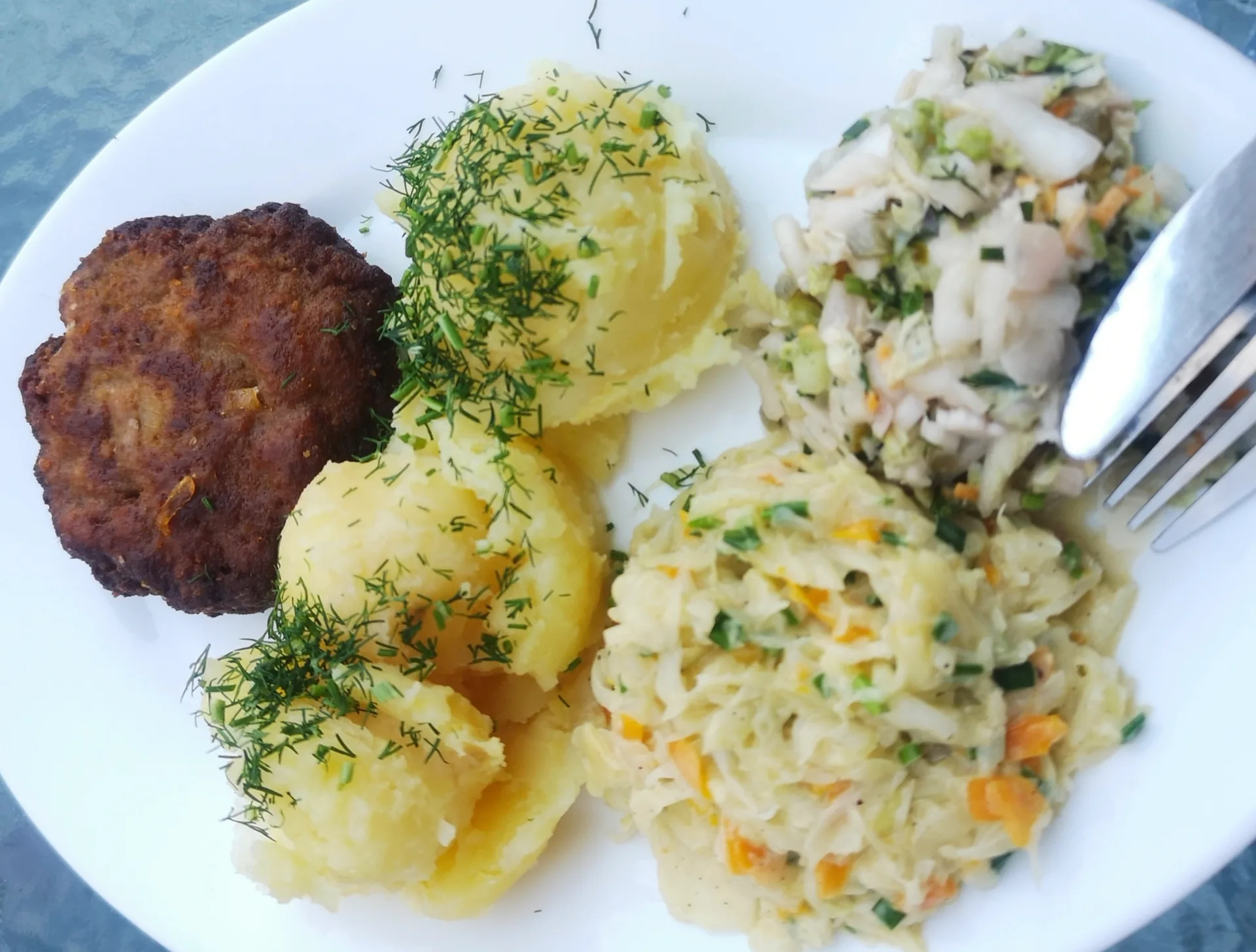 A Frikadelle served with vegetables and potatoes.