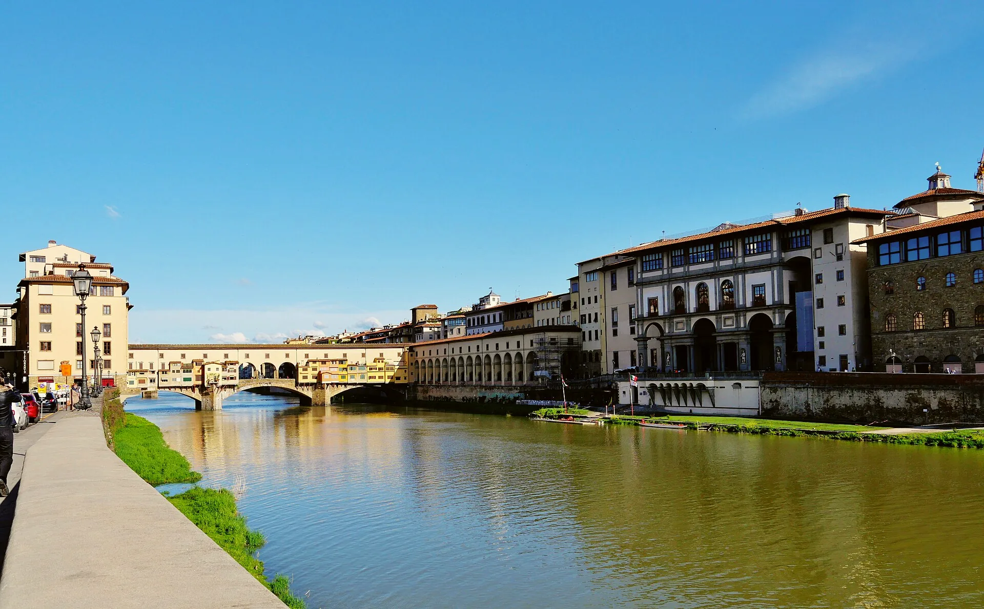 The Arno flowing beneath Ponte Vecchio in Florence, with buildings lining the river.