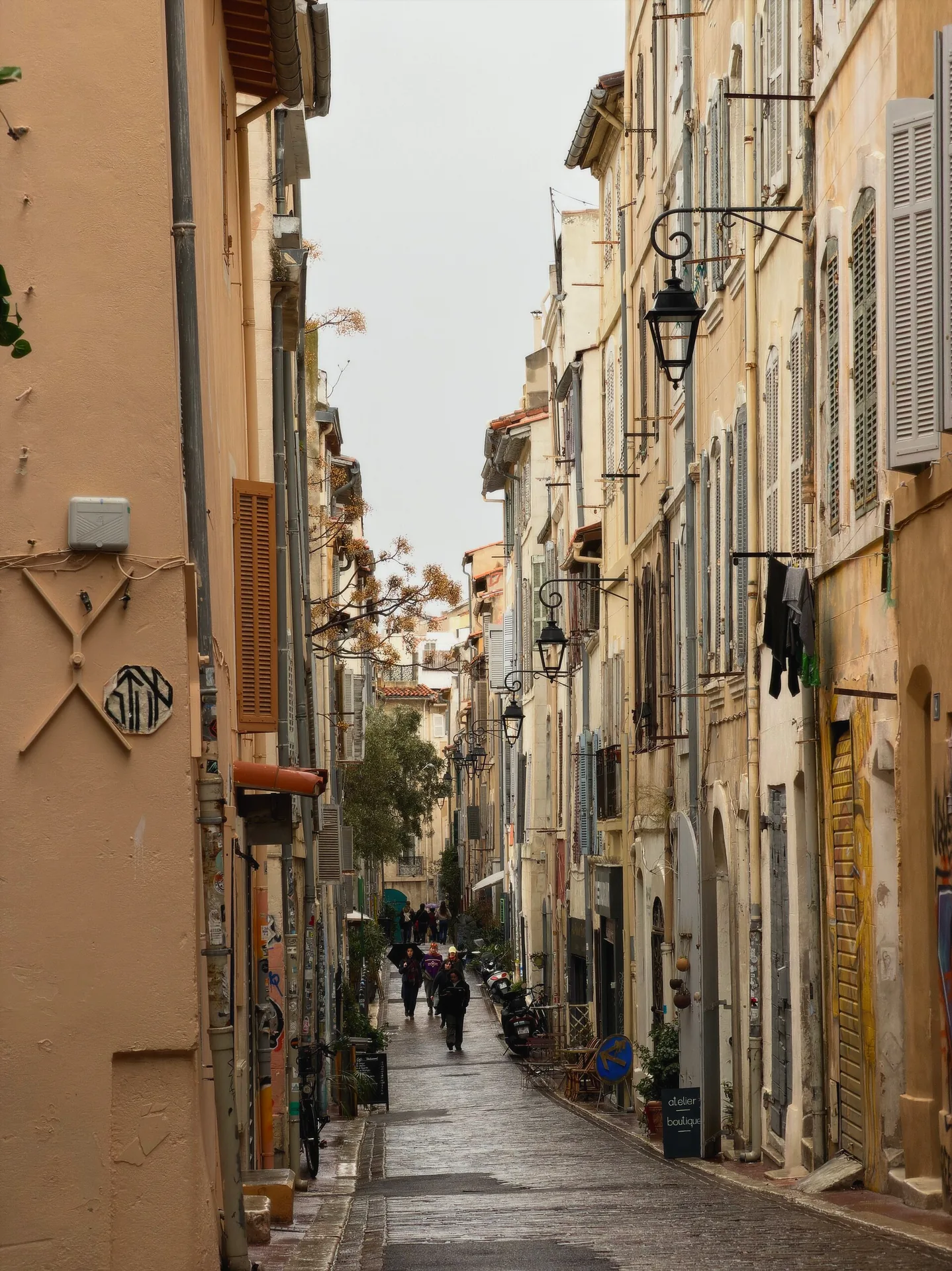A narrow pedestrian street in Le Panier, lined with historic buildings and shutters.