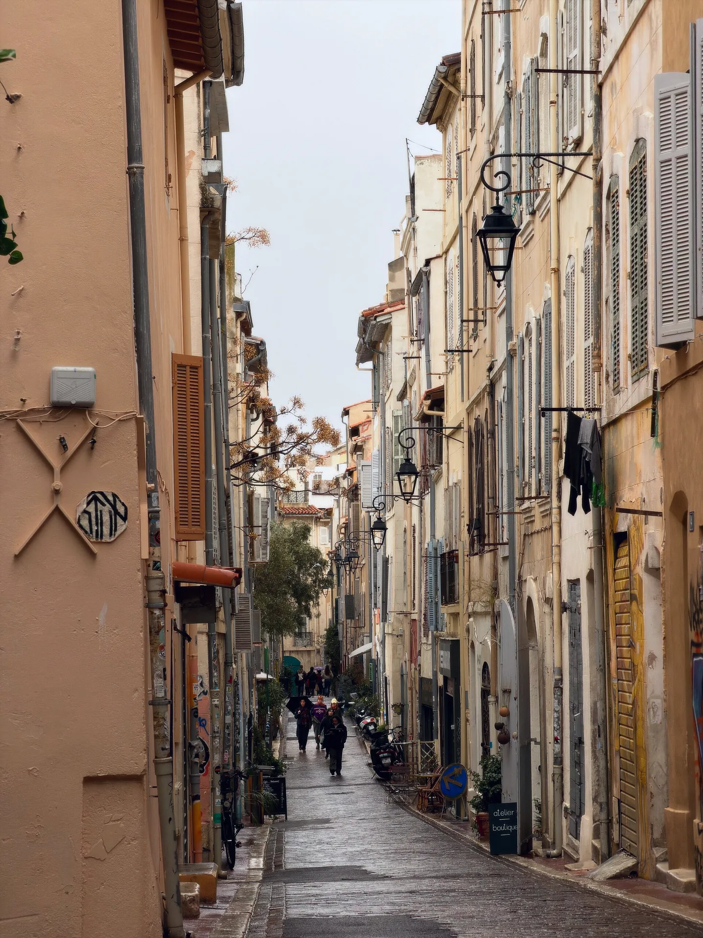 A narrow pedestrian street in Le Panier, with pastel-coloured façades, wooden shutters and wall-mounted street lamps.