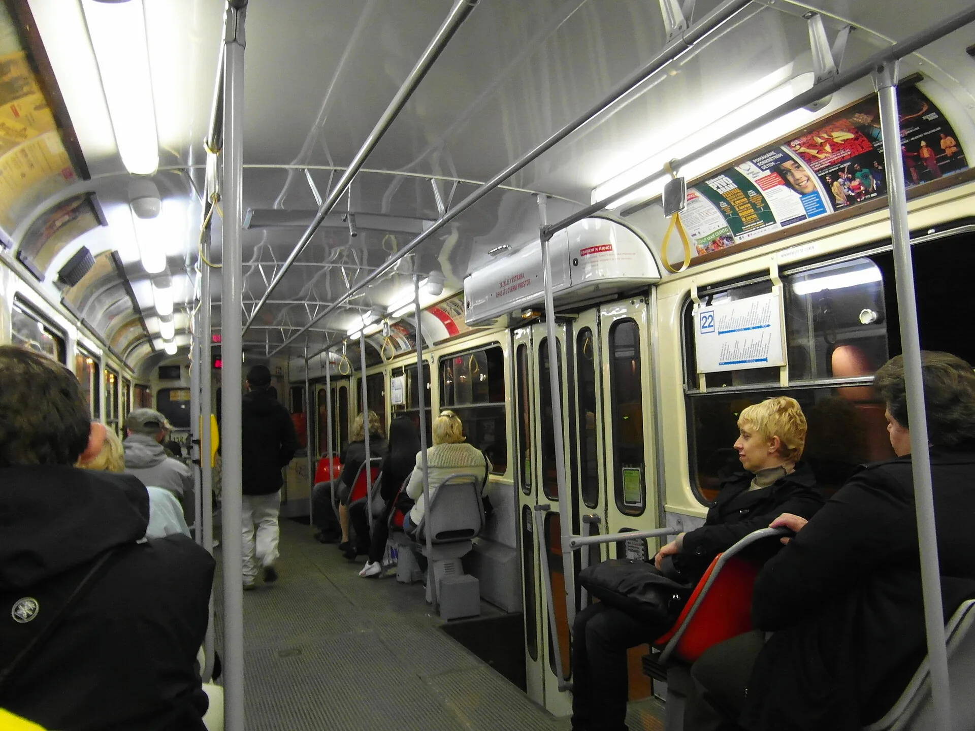 Interior of a Tatra T3 tram in Prague, with rows of seats and handrails.