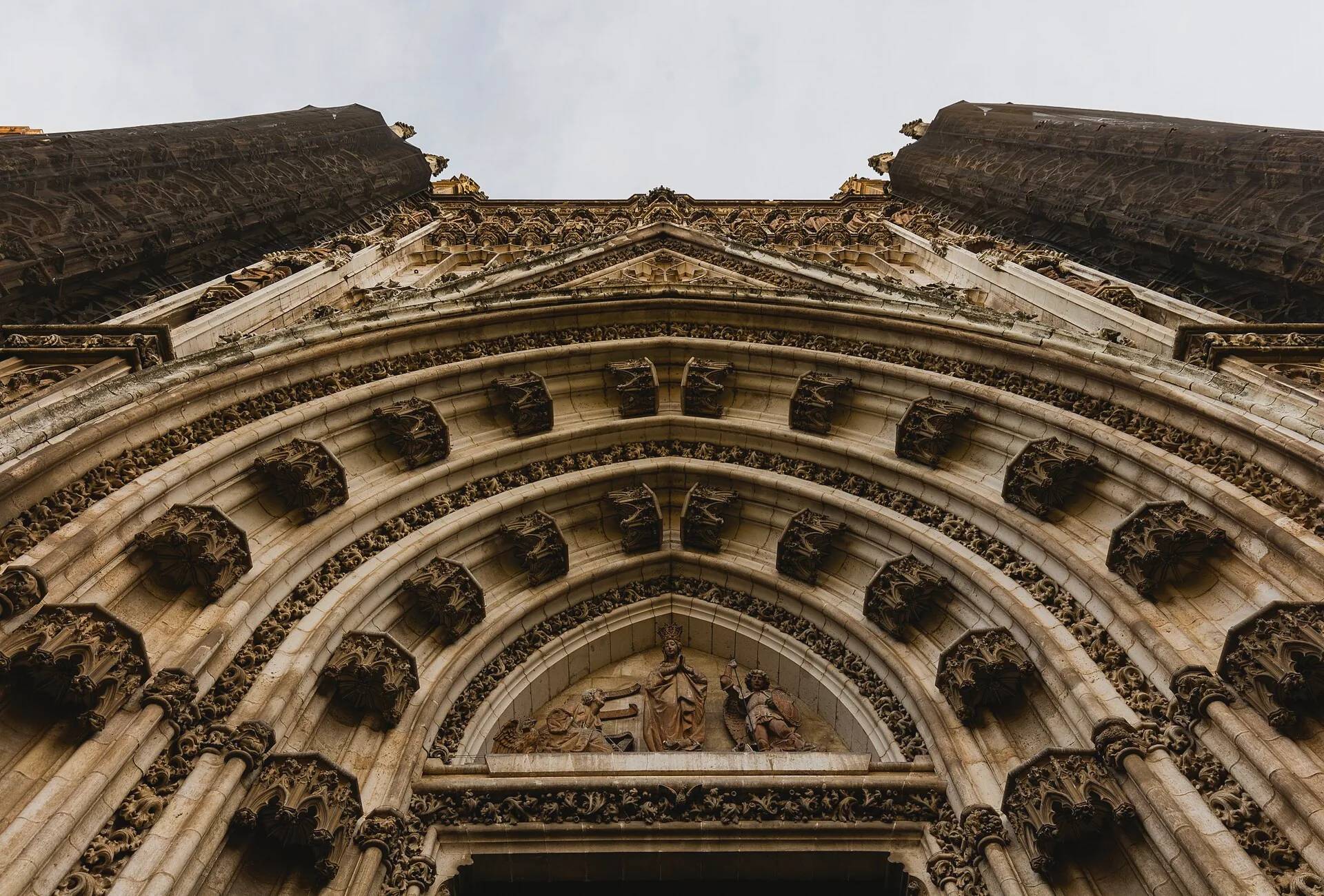Ornate stone entrance at Seville Cathedral, framed by sculpted columns and carved figures.