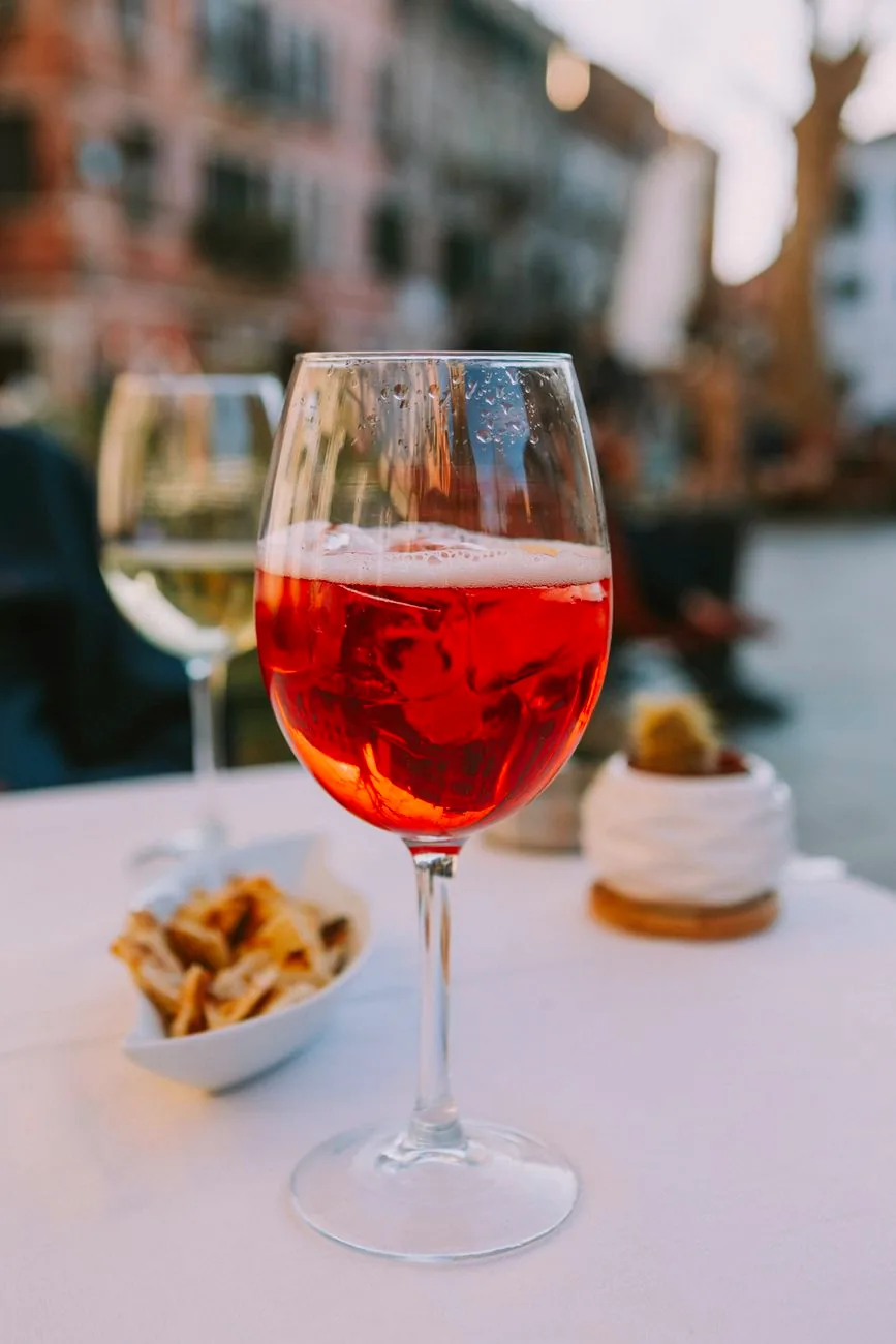 An Aperol spritz with small appetisers on an outdoor table.