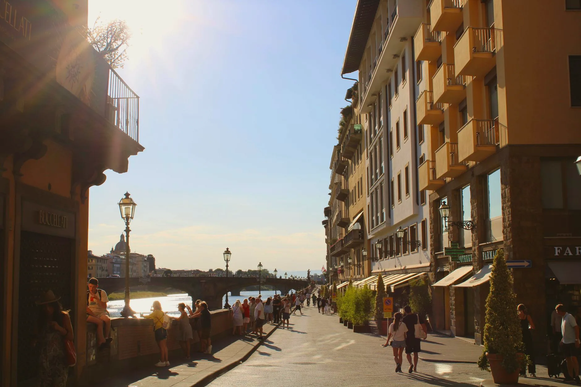 People strolling along a sunlit street in Florence.