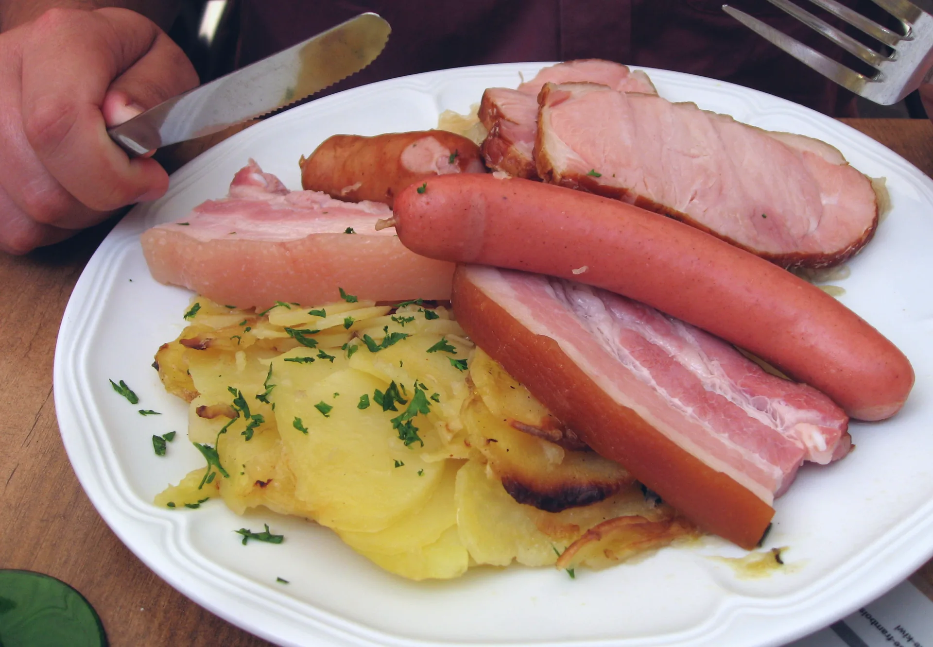 A plate of sauerkraut served with potatoes and several kinds of meat.
