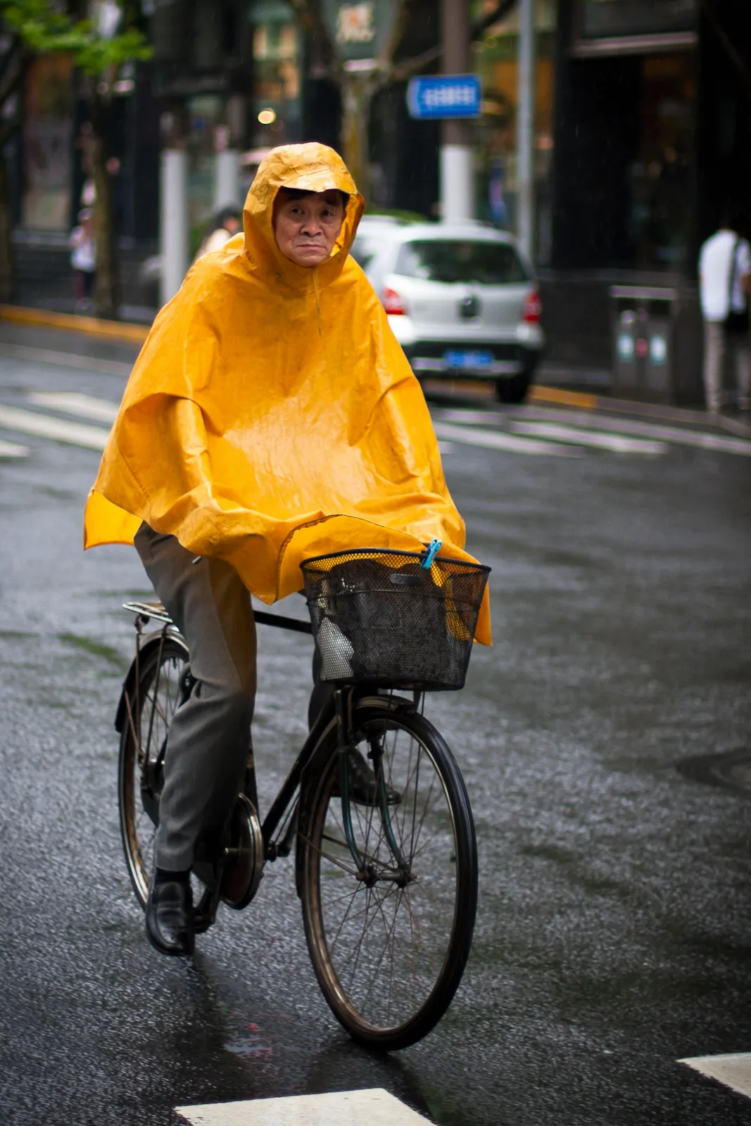 A cyclist wearing a yellow rain poncho in Shanghai.
