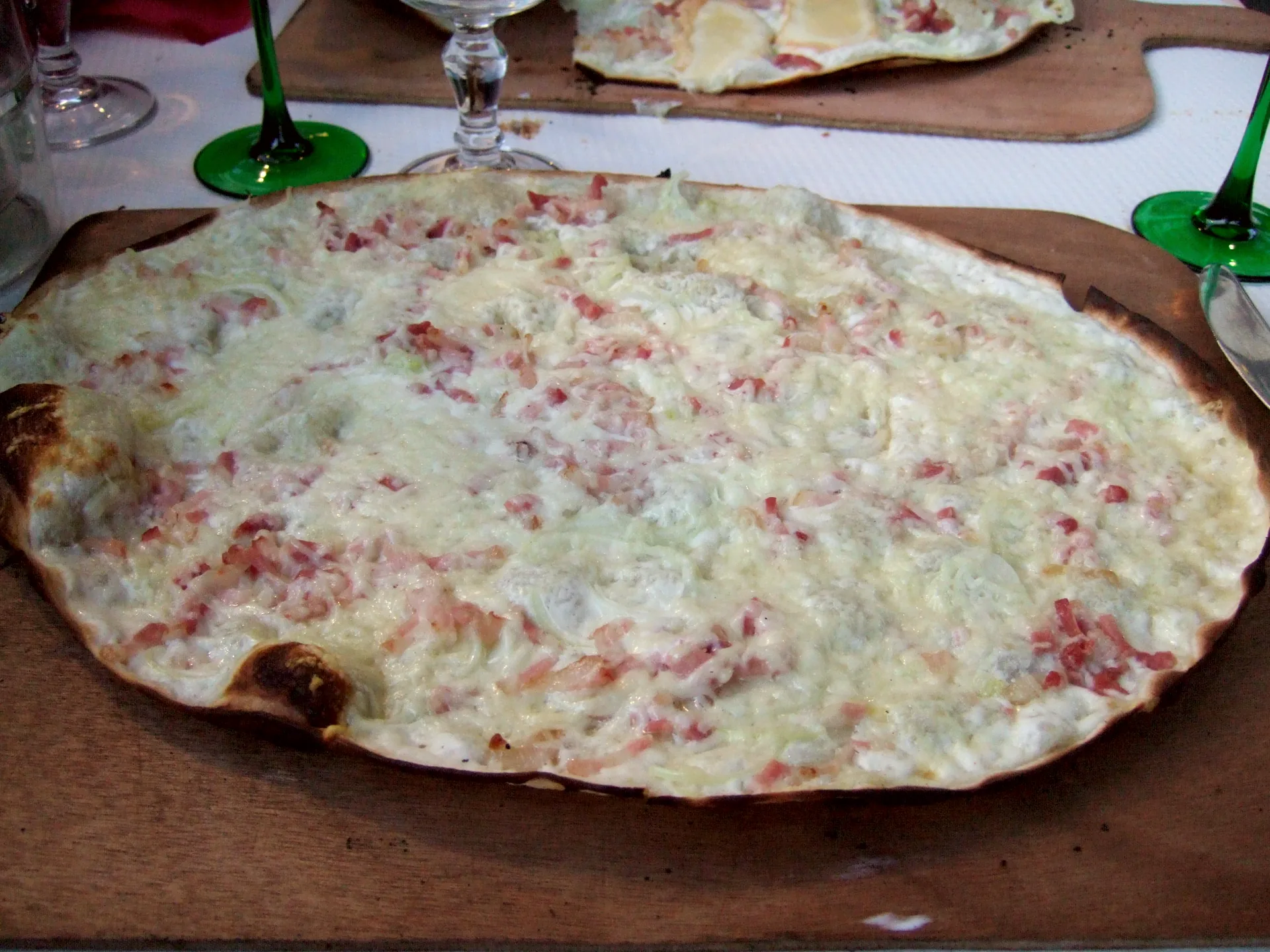 A round Alsatian flammekueche topped with cheese, onions and bacon.