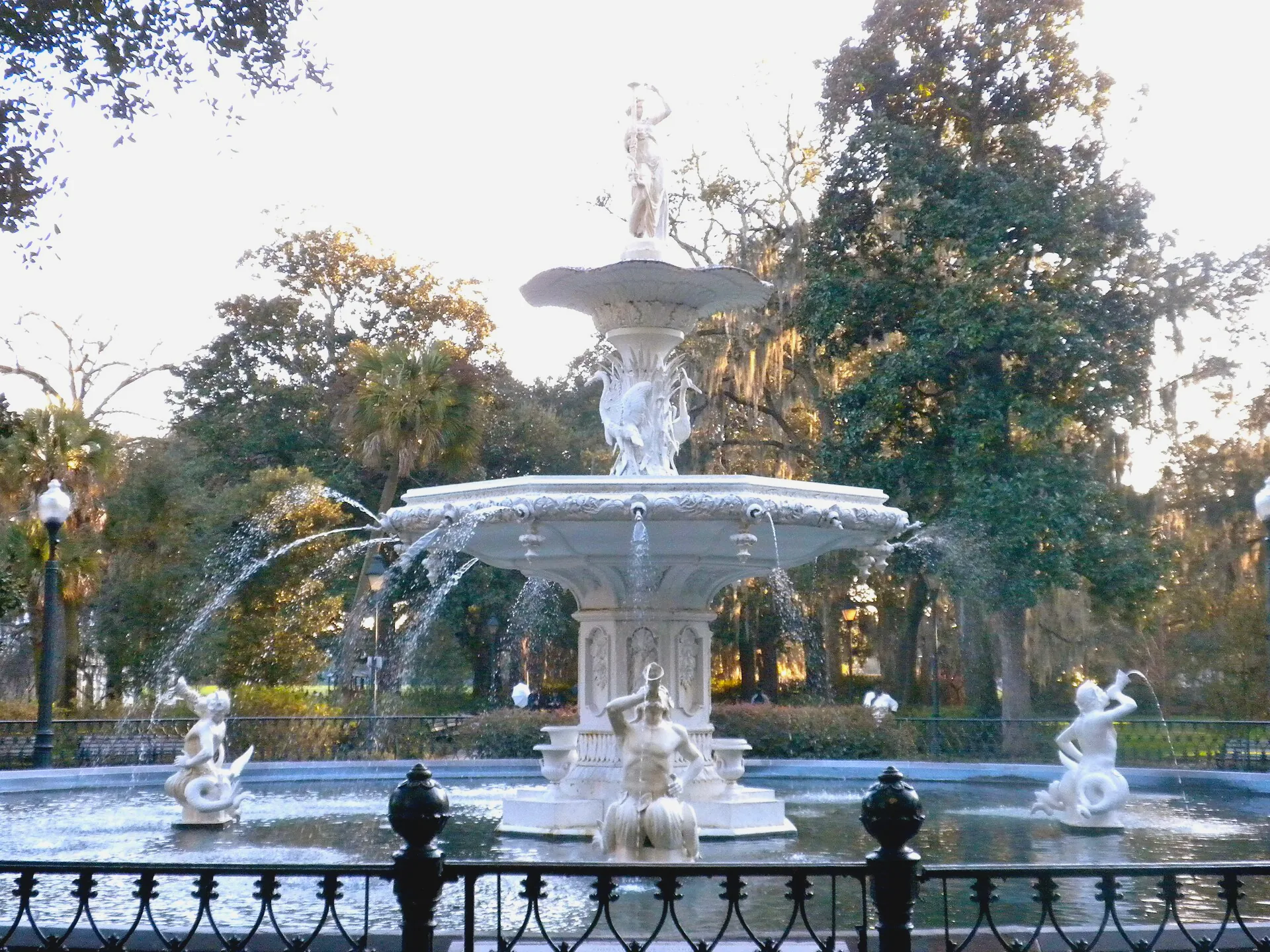 The ornate, two-tiered cast-iron fountain in Forsyth Park, with water spilling into its surrounding pool.