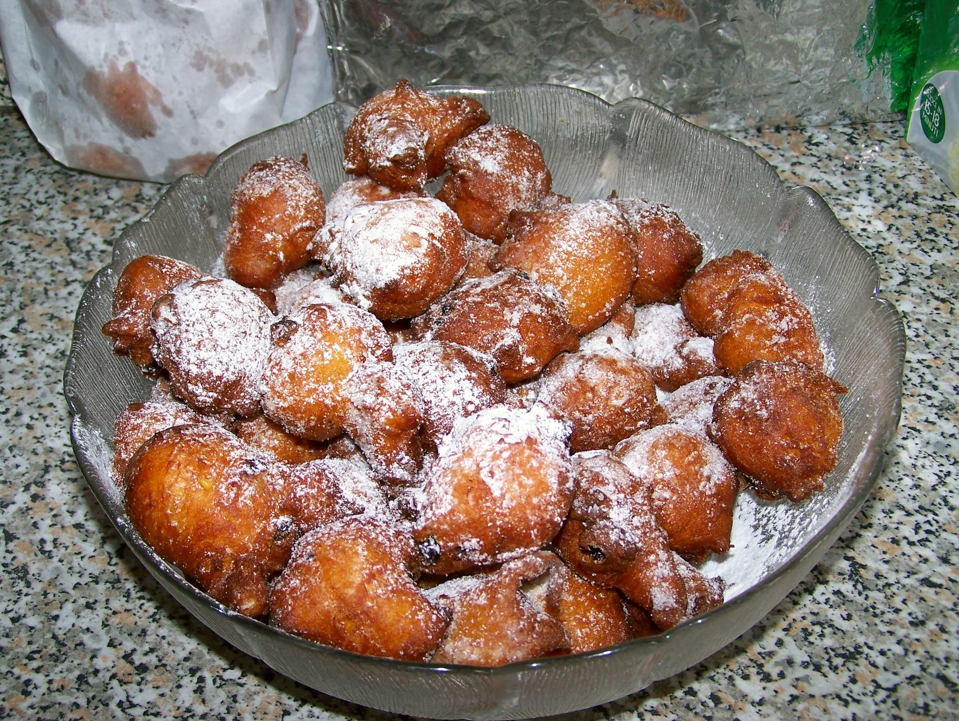 A pile of small golden carnival fritole dusted with icing sugar.