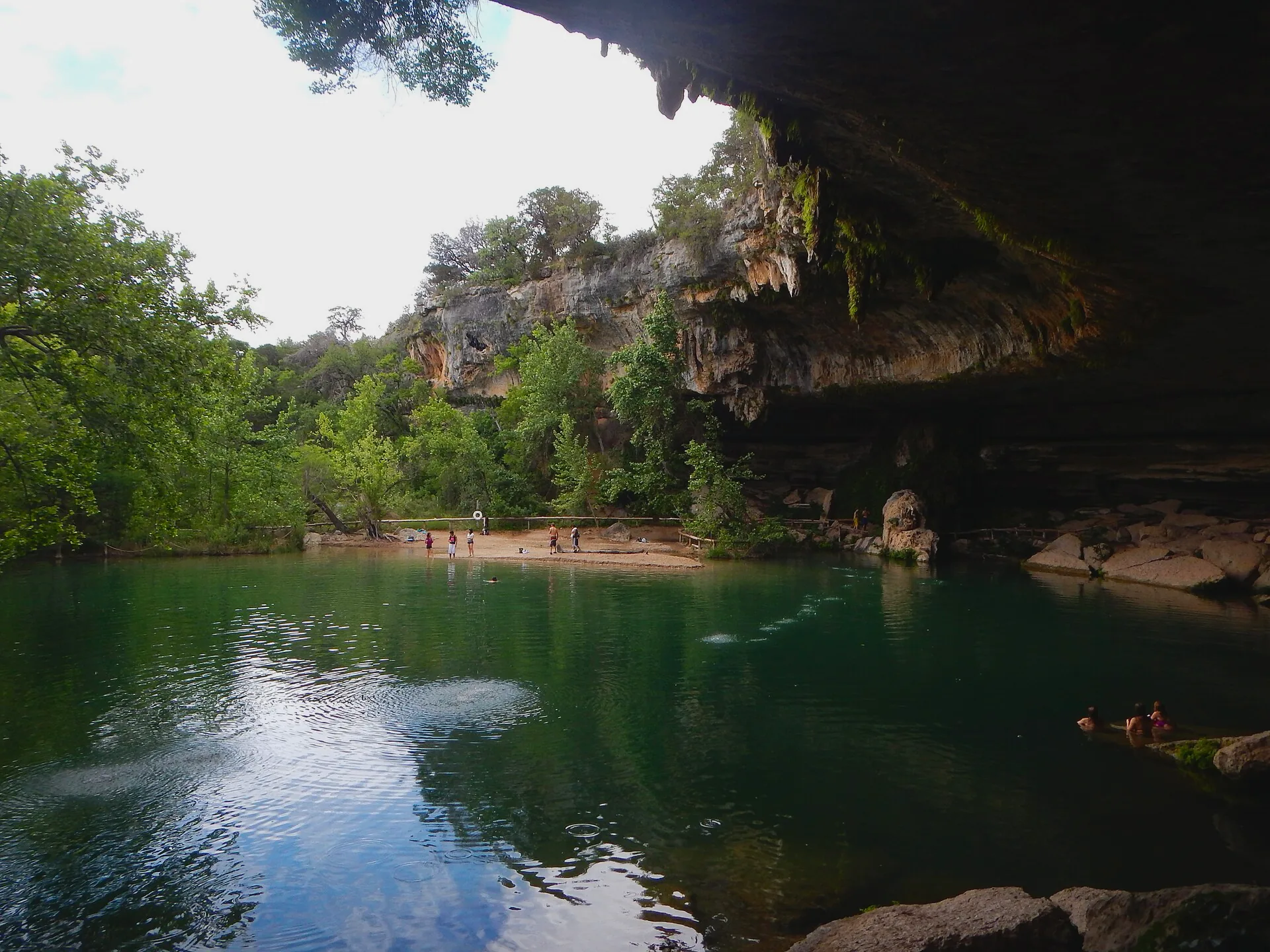 A grotto at Hamilton Pool, with water beneath a rocky overhang.