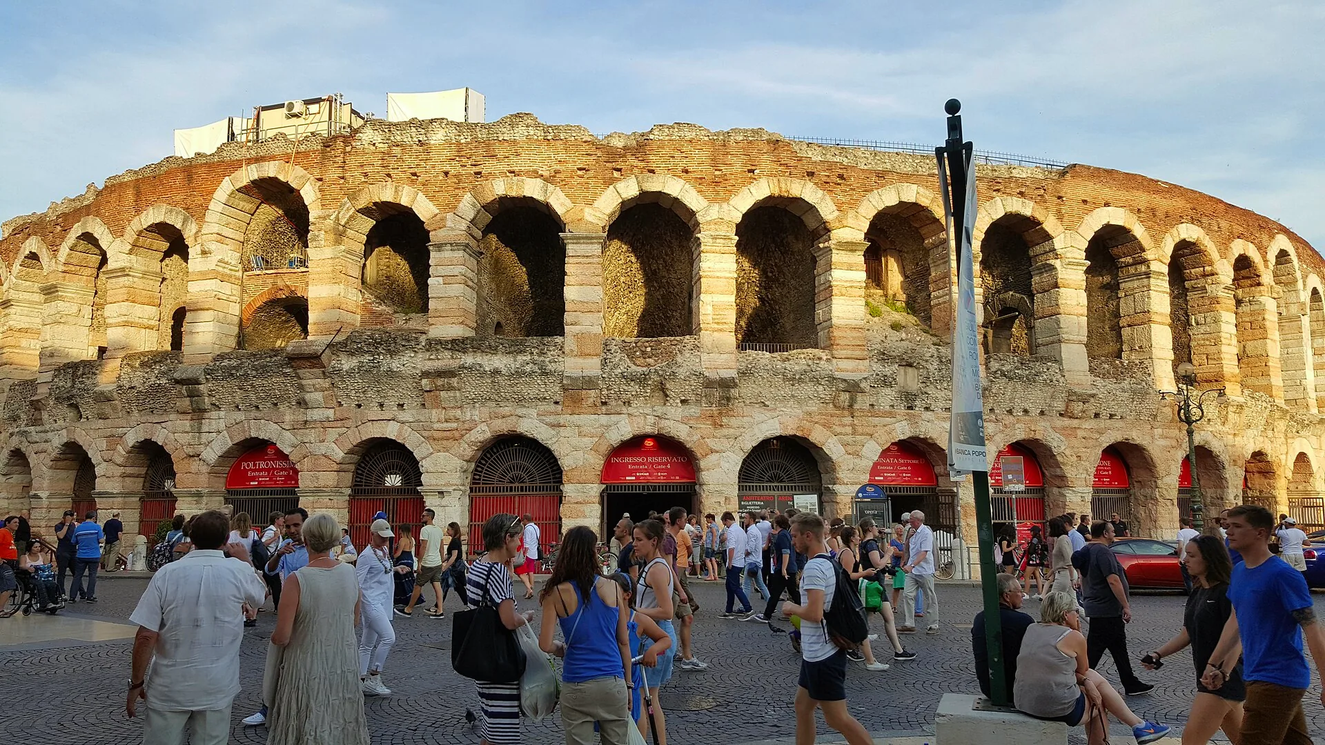 The Verona Arena seen from outside, with its curved stone façade and rows of arches.