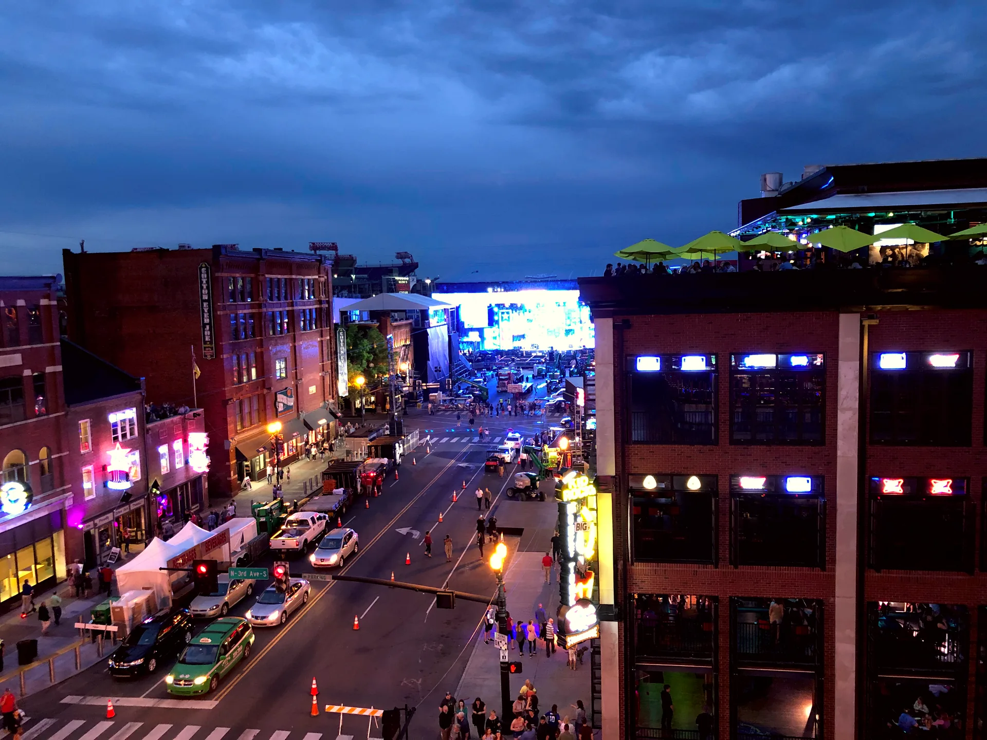 A view down Lower Broadway in Nashville from a rooftop, with workers setting up a stage in the distance.