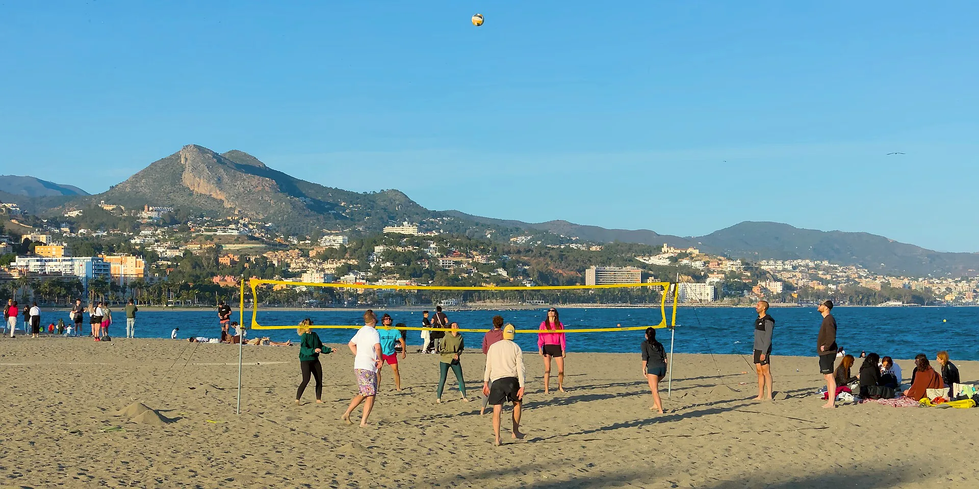 People playing beach volleyball on Playa de la Malagueta shortly before sunset.