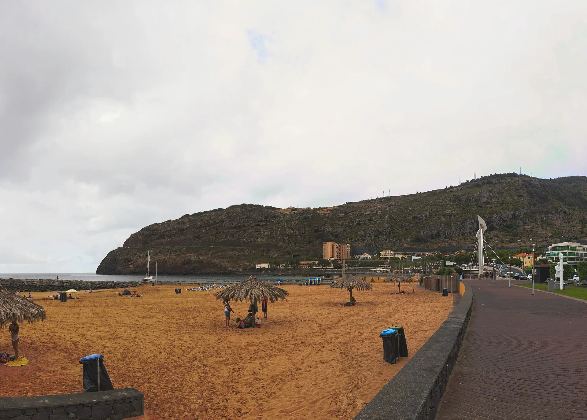 The sandy beach at Machico beside the sea, with the town and hills beyond.