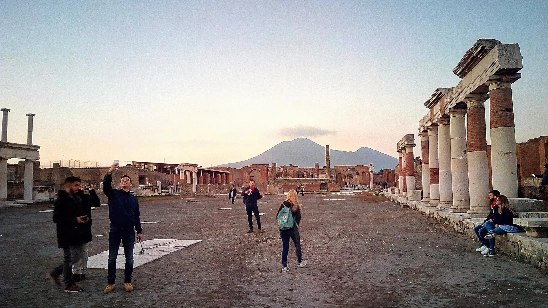 The open square of the Forum at Pompeii, bordered by ancient columns and ruins.