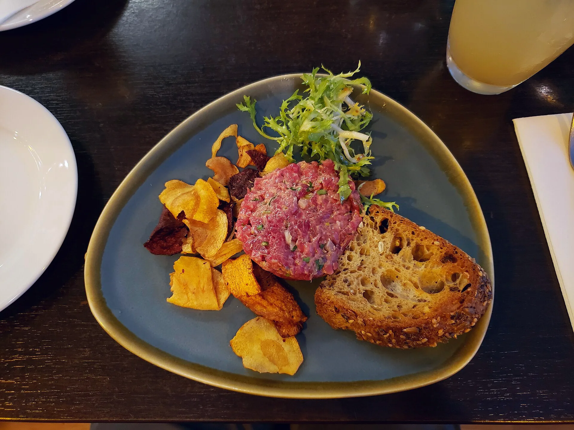 Steak tartare served with vegetable crisps and toasted bread.