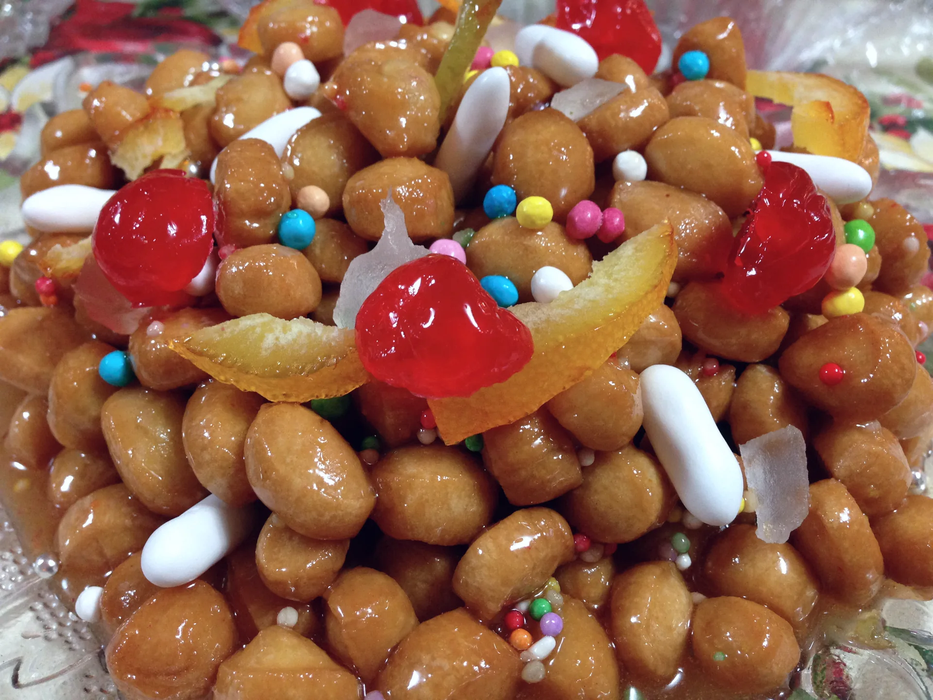 A plate of Neapolitan struffoli, small fried dough balls coated in honey and colourful sprinkles.