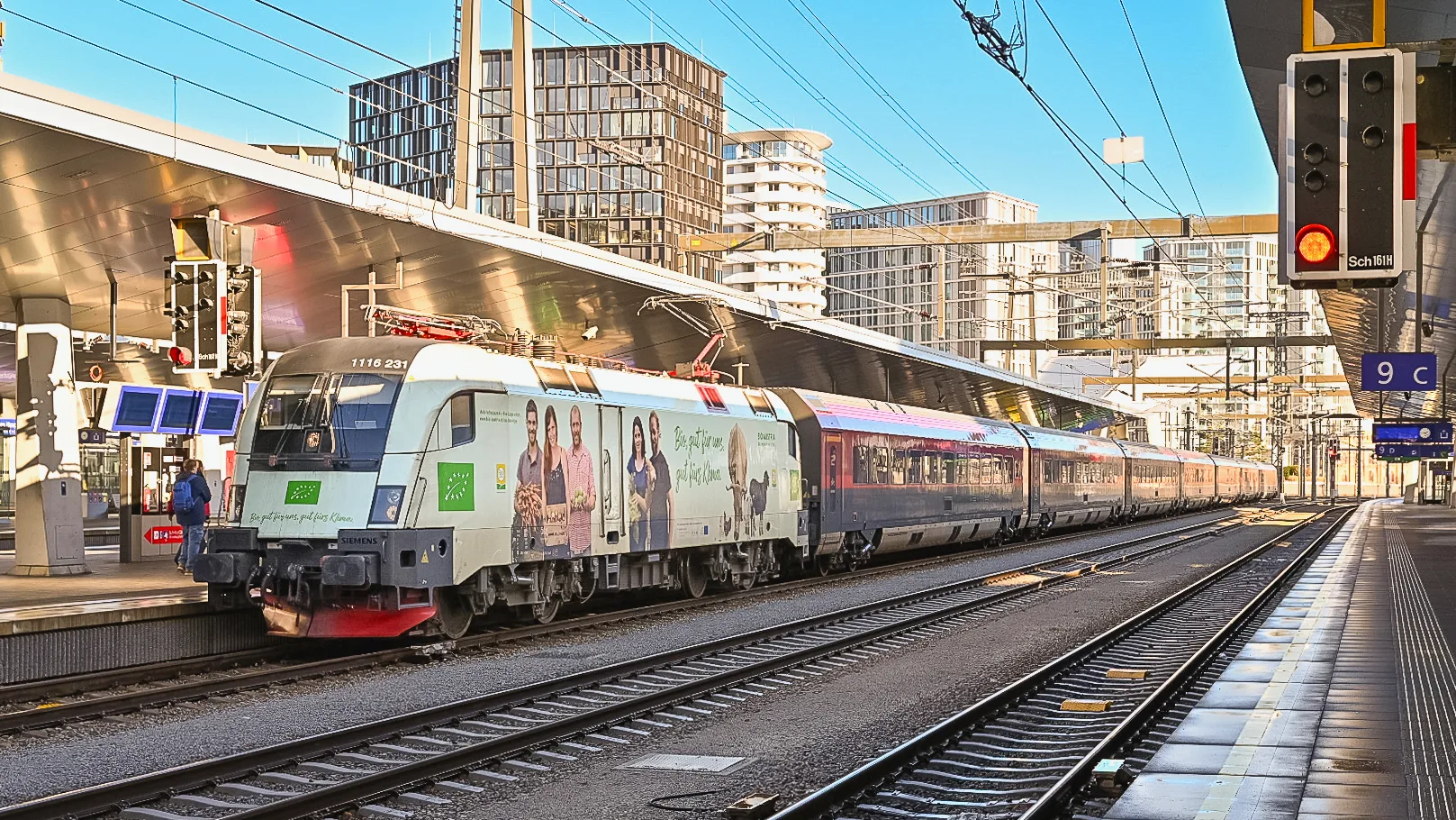 An ÖBB Railjet train at Wien Hauptbahnhof, hauled by a red-and-white Taurus locomotive.