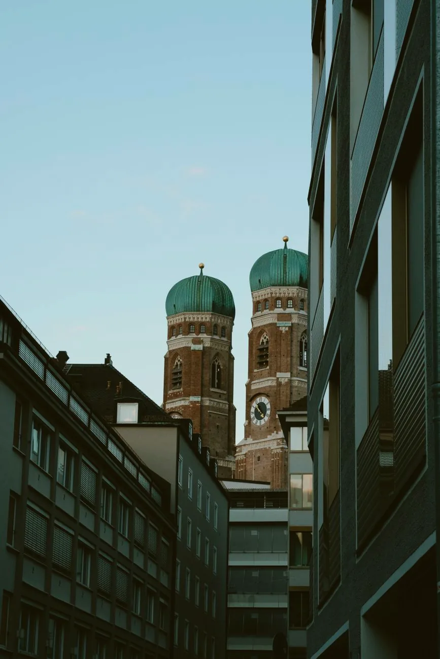 The twin towers of Munich’s Frauenkirche rise between modern city buildings.