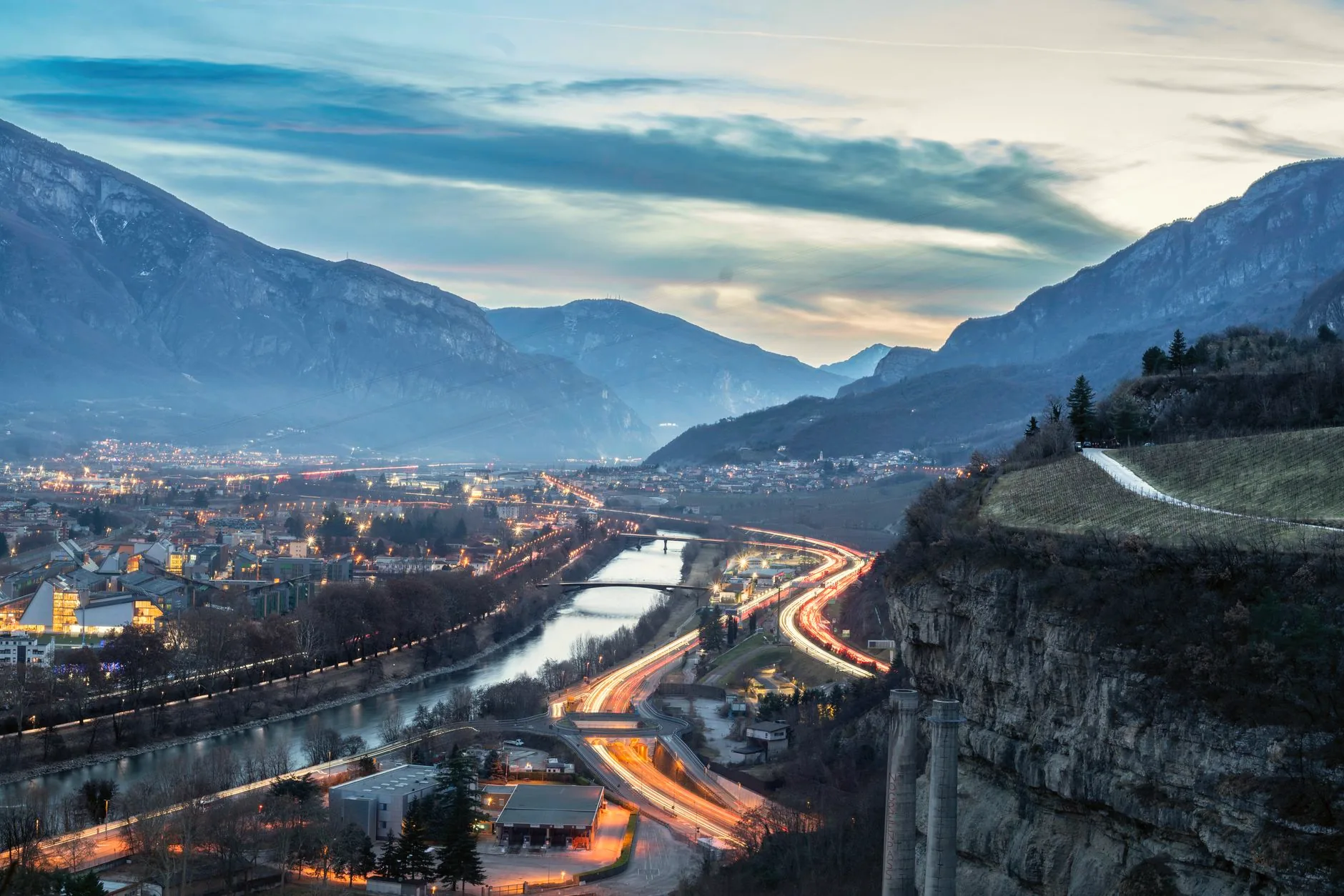 Aerial view of Trento, with the Adige River, roads and mountains surrounding the city.