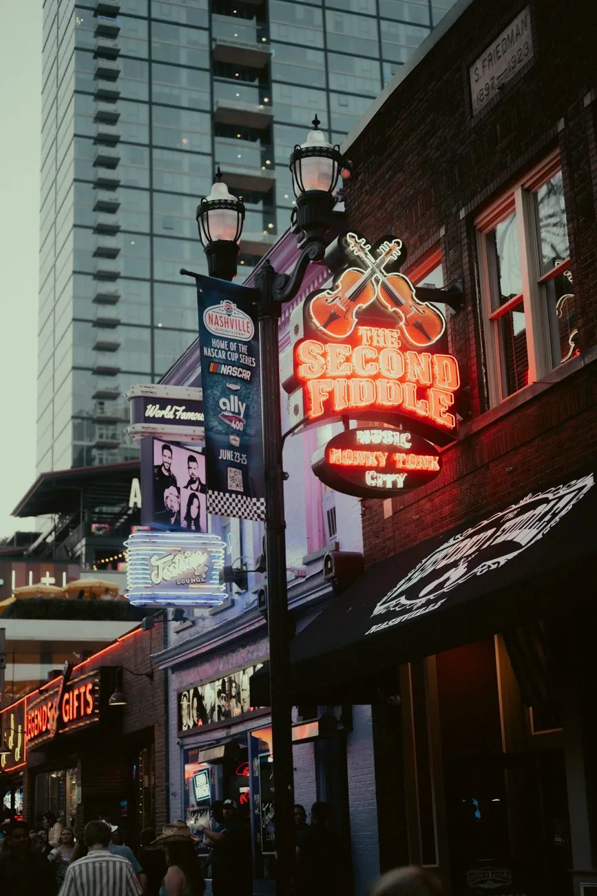 Neon signs illuminate Broadway in Nashville at night.
