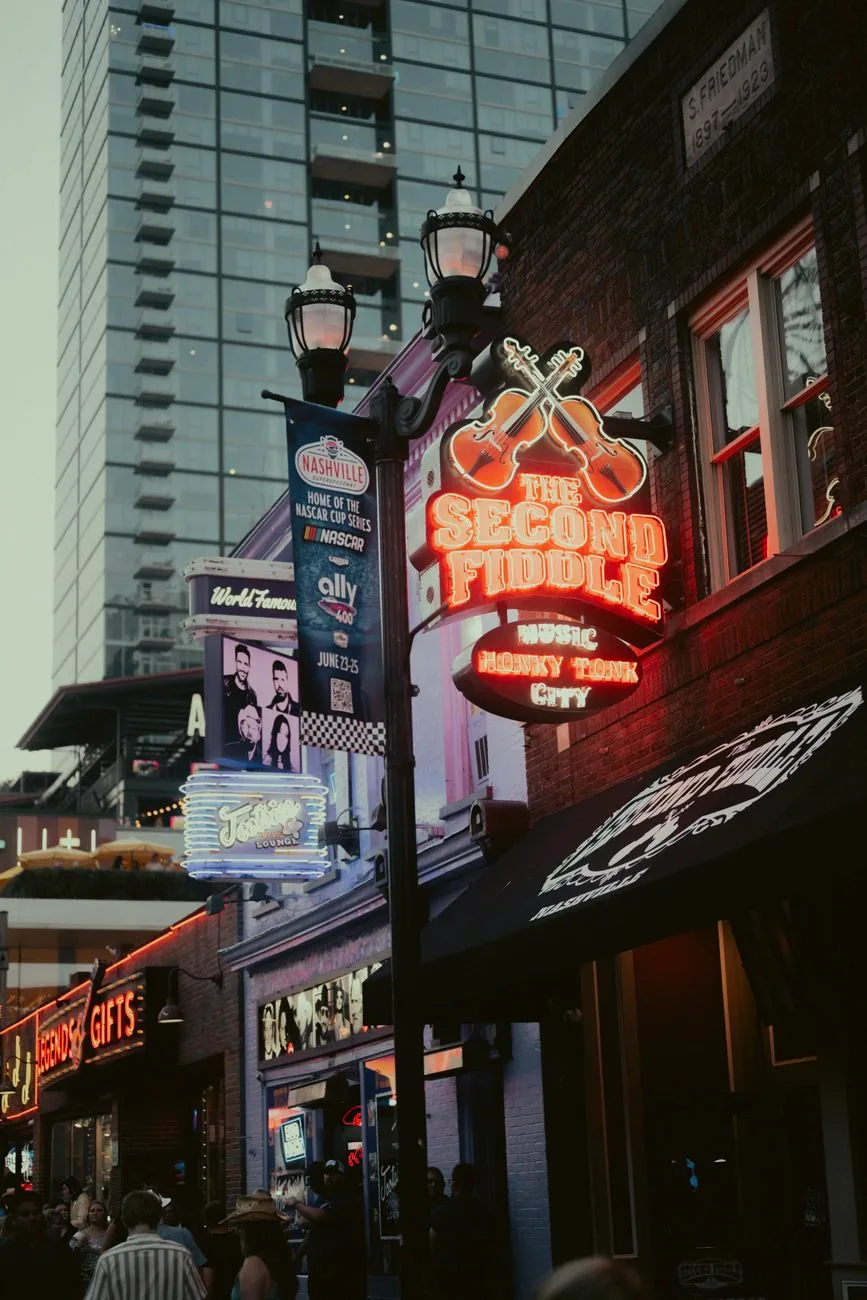 Neon signs illuminate Broadway in Nashville at night.