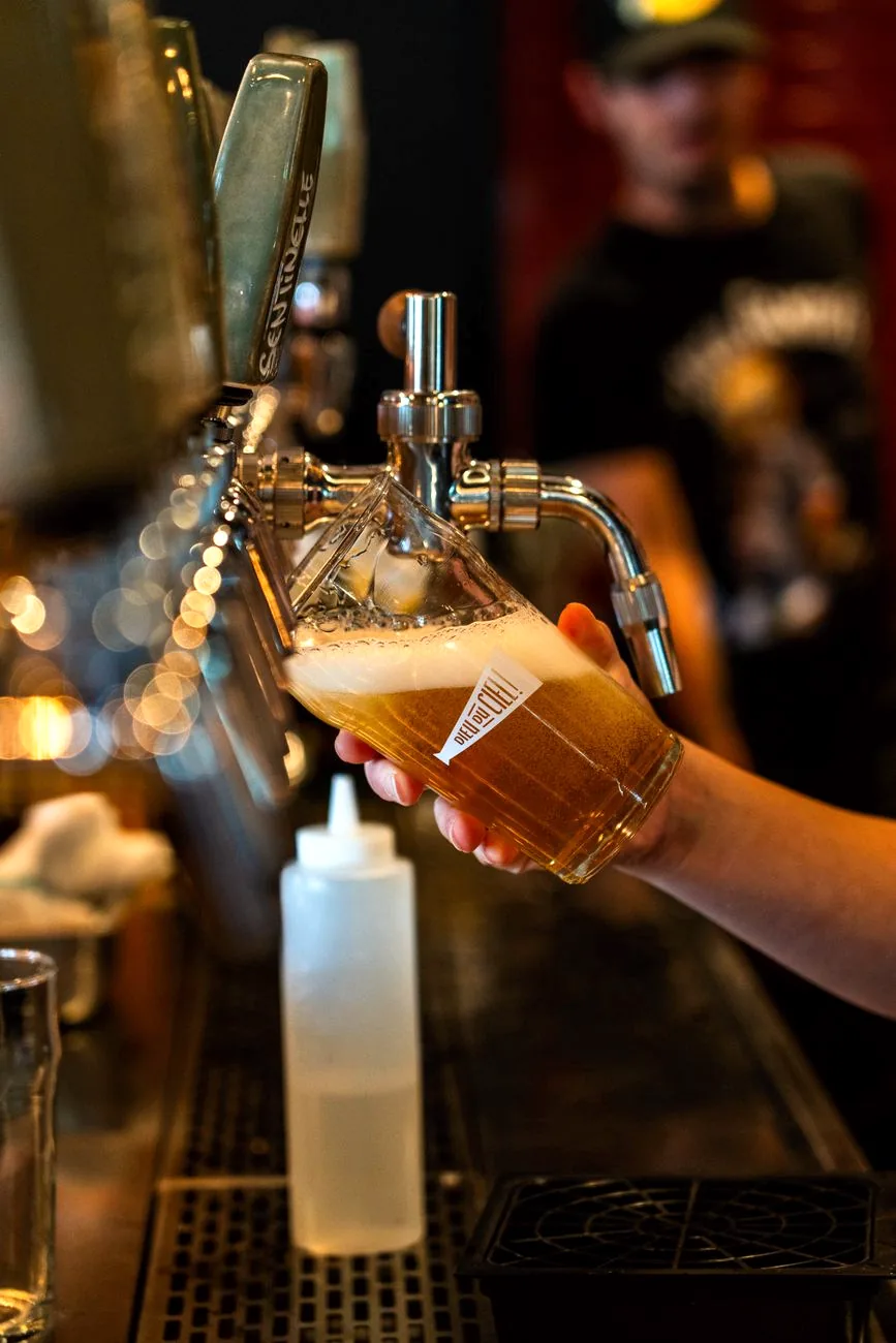 A pint of craft beer being poured from a draught tap.