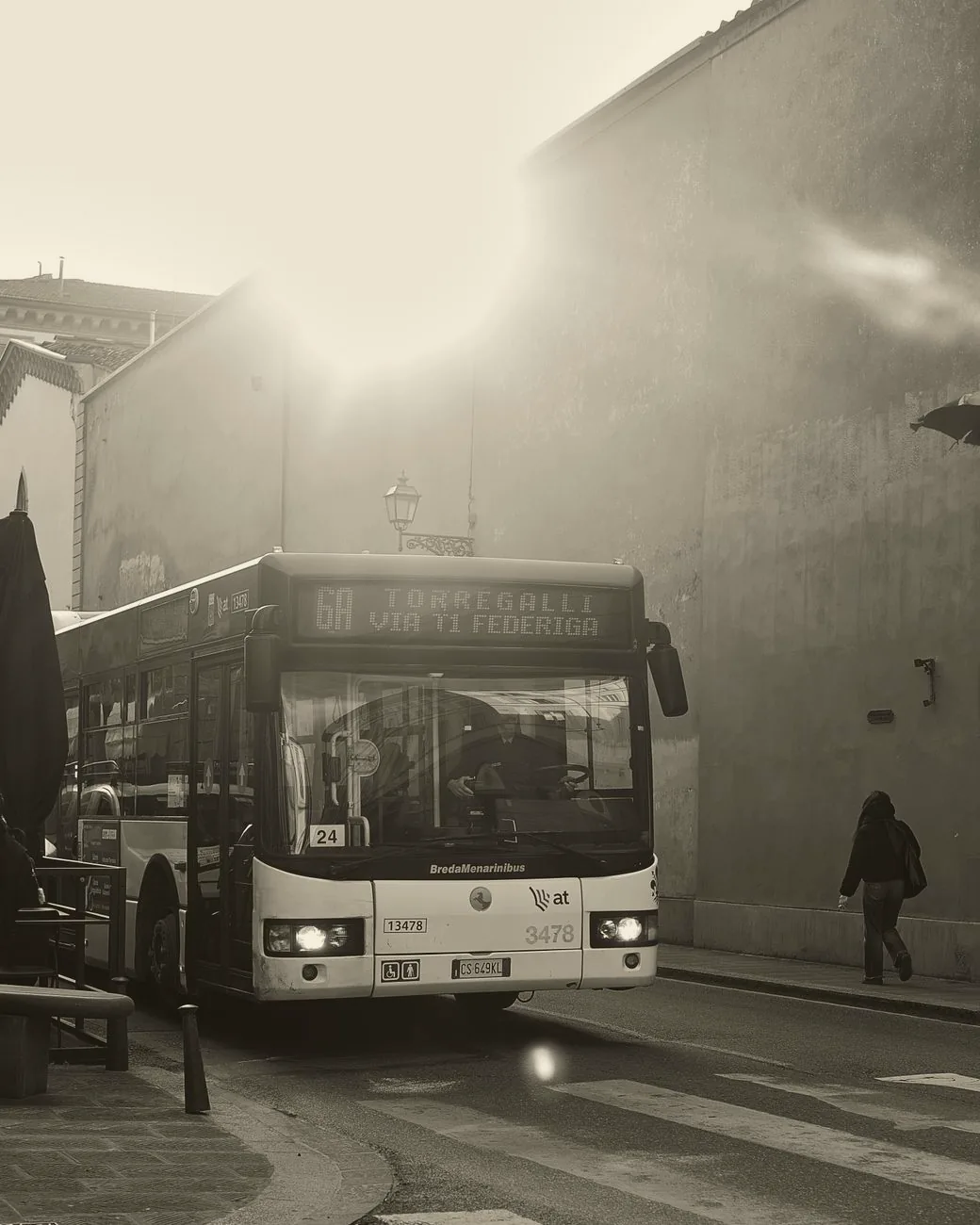 A city bus travels along a street in Florence, with pedestrians and buildings nearby.