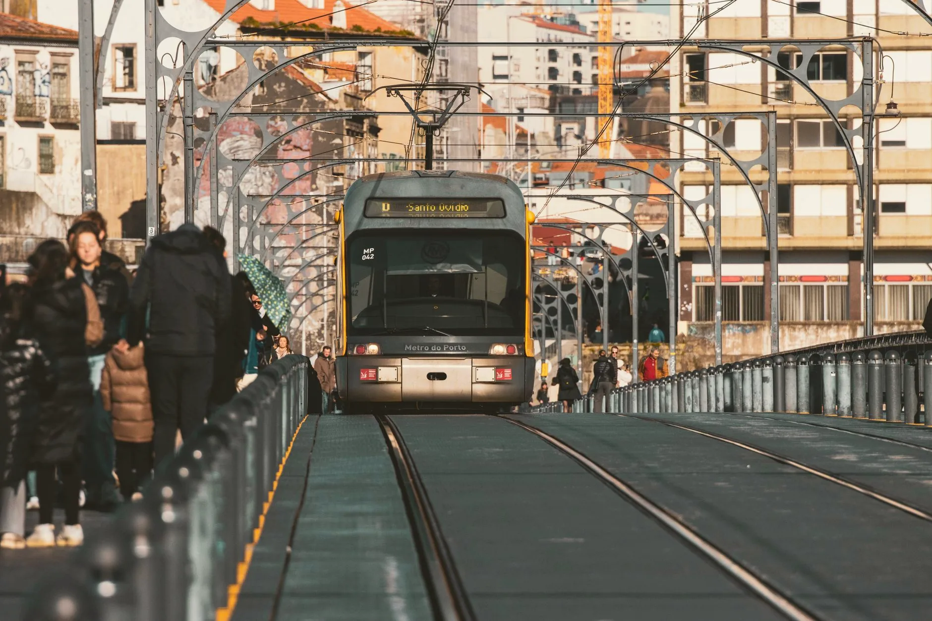 A Metro do Porto train crosses the Ponte Luís I bridge above the river, with Porto’s buildings beyond.