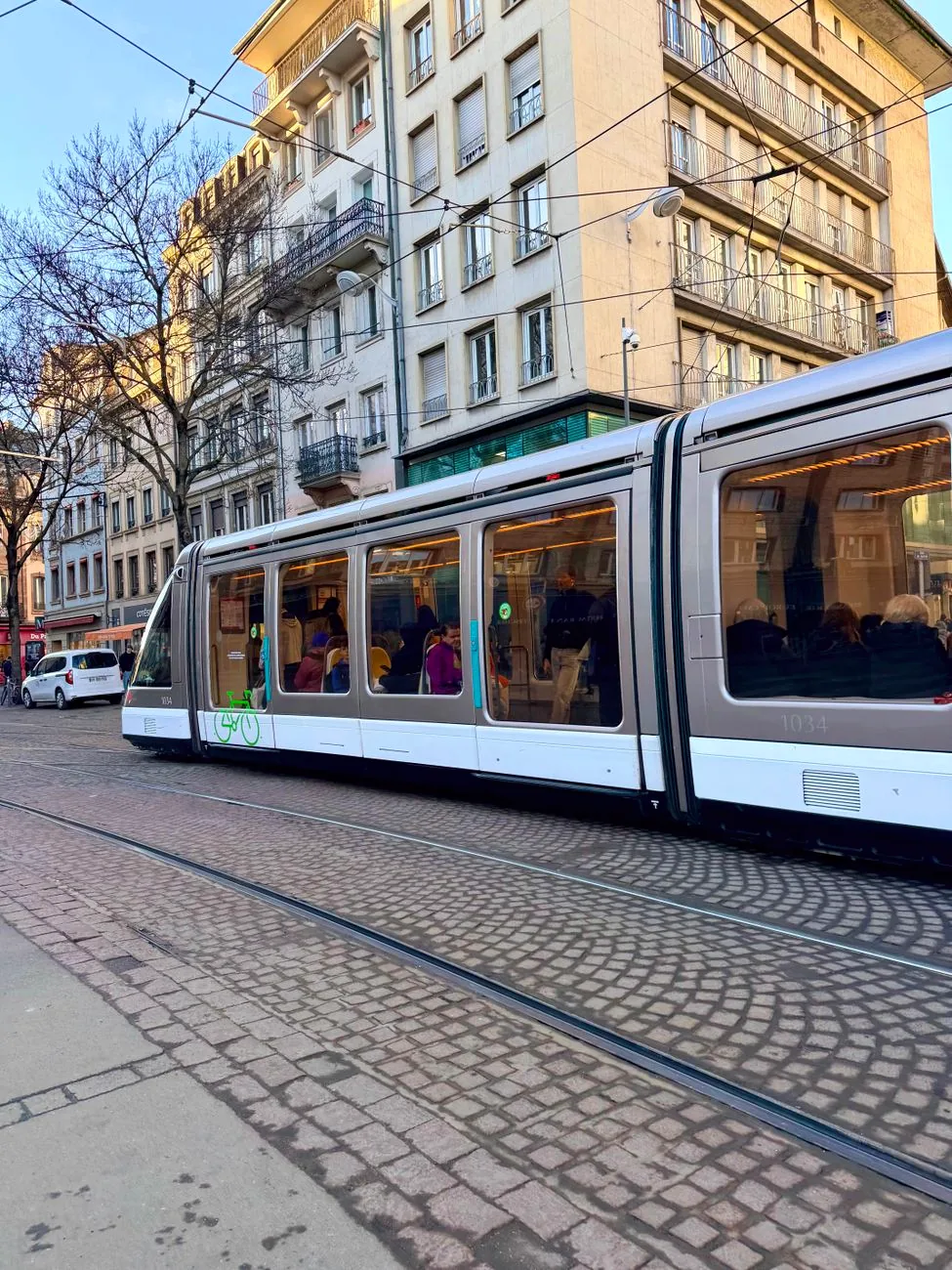 A modern tram travelling along a street in Strasbourg, with buildings on either side.