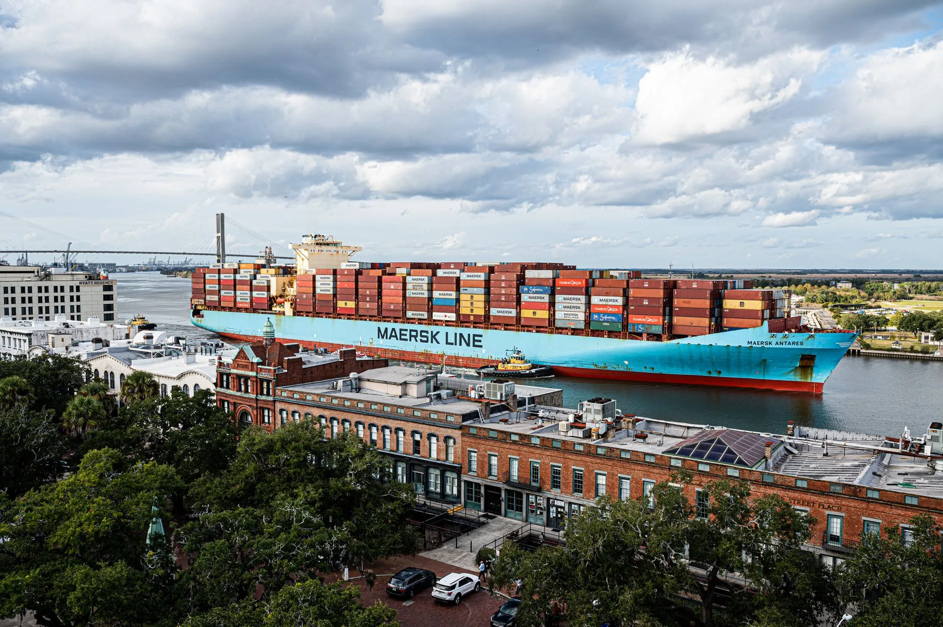 A cargo ship moves along the Savannah River with the city in the background.